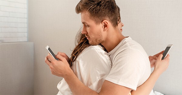 Couple Hugging and Using Phones behind Each Other’s Backs