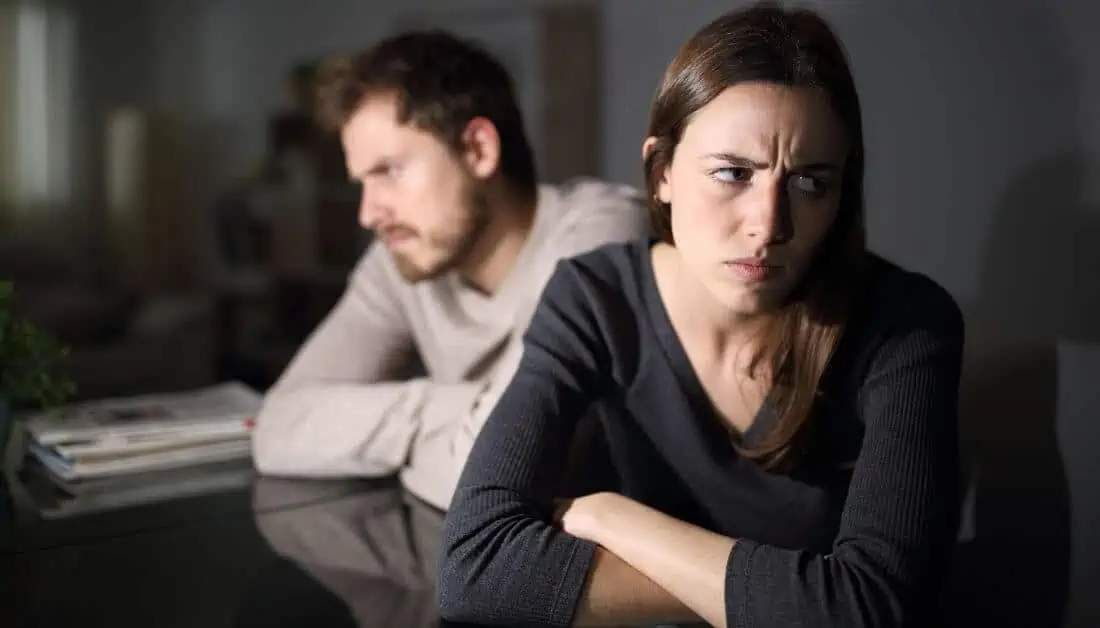 Man and woman sitting at table facing away from each other, angry