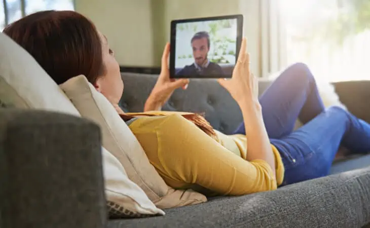 Woman Laying Down in a Sofa Video Chatting with a Man