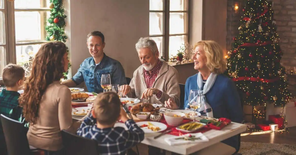 Family sitting together having a holiday dinner with Christmas tree in the background