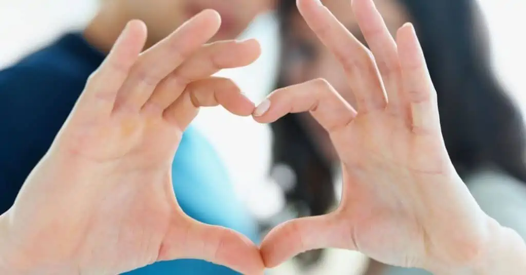 Man and woman forming hands together to shape a heart