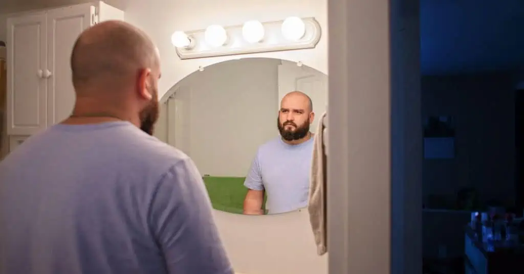 Man with low self-esteem looking in the mirror