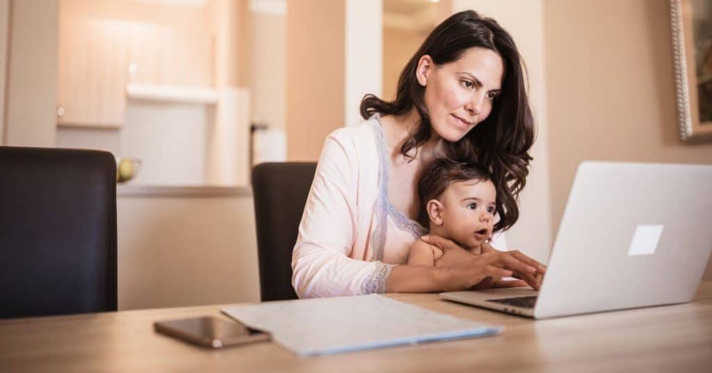 Single mom working on a computer with her child in her lap